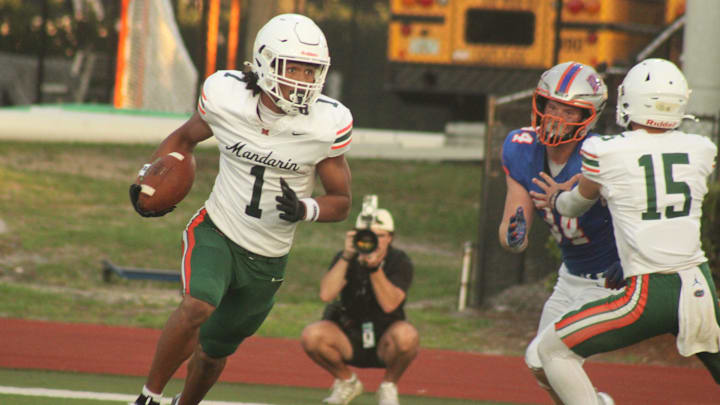 Mandarin wide receiver Brysen Wright (1), with help from blocking quarterback Knox Annis (15), tries to escape from Bolles defensive end Asher Ghioto (34) after returning into his own backfield on his way to a 77-yard touchdown reception during a high school spring football game on May 22, 2025. [Clayton Freeman/Florida Times-Union]