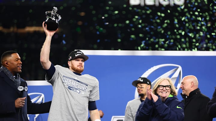 Jan 25, 2026; Seattle, WA, USA; Seattle Seahawks quarterback Sam Darnold (14) celebrates with the trophy on the podium after defeating the Los Angeles Rams in the 2026 NFC Championship Game at Lumen Field.