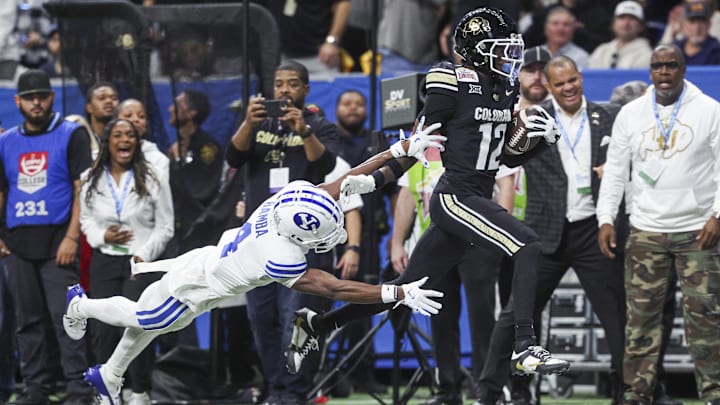 Dec 28, 2024; San Antonio, TX, USA; Colorado Buffaloes wide receiver Travis Hunter (12) runs with the ball as Brigham Young Cougars cornerback Mory Bamba (4) attempts to make a tackle during the second quarter at Alamodome.  