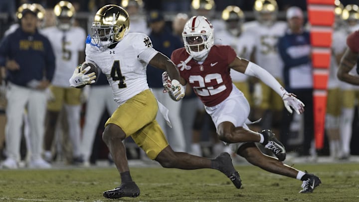 Nov 29, 2025; Stanford, California, USA;  Notre Dame Fighting Irish running back Jeremiyah Love (4) runs with the football during the first quarter against Stanford Cardinal safety Che Ojarikre (22) at Stanford Stadium. Mandatory Credit: Stan Szeto-Imagn Images
