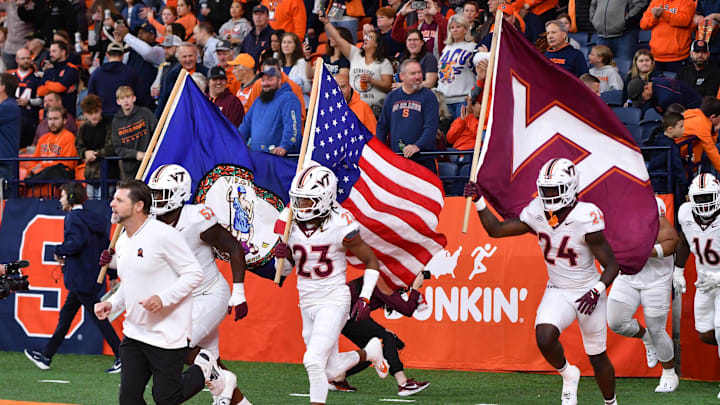Nov 2, 2024; Syracuse, New York, USA; Virginia Tech Hokies cornerback Thomas Williams (23) carries the American flag onto the field with his team before a game against the Syracuse Orange at JMA Wireless Dome. Mandatory Credit: Mark Konezny-Imagn Images