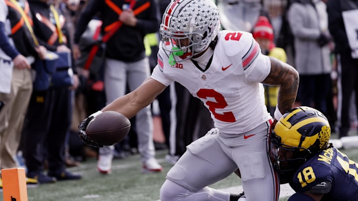 Nov 25, 2023; Ann Arbor, Michigan, USA; Ohio State Buckeyes wide receiver Emeka Egbuka (2) is hit by Michigan Wolverines defensive back Ja'Den McBurrows (18) as he scores a touchdown in the first half against the Michigan Wolverines at Michigan Stadium. 