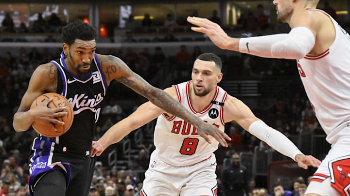 Jan 12, 2025; Chicago, Illinois, USA;  Sacramento Kings guard Malik Monk (0) drives to the basket against Chicago Bulls guard Zach LaVine (8) and  center Nikola Vucevic (9) during the second half at United Center. Mandatory Credit: Matt Marton-Imagn Images