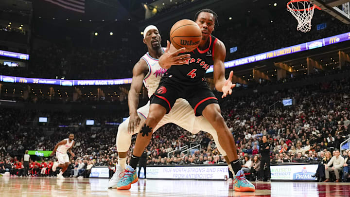 Feb 21, 2025; Toronto, Ontario, CAN;  Toronto Raptors forward Scottie Barnes (4) battles for a loose ball against Miami Heat center Bam Adebayo (13) during the first half at Scotiabank Arena. Mandatory Credit: Kevin Sousa-Imagn Images