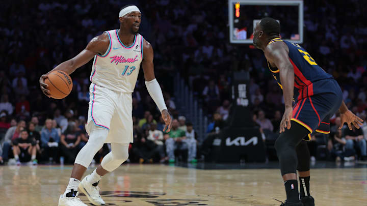 Mar 25, 2025; Miami, Florida, USA; Miami Heat center Bam Adebayo (13) dribbles the basketball as Golden State Warriors forward Draymond Green (23) defends during the third quarter at Kaseya Center. Mandatory Credit: Sam Navarro-Imagn Images