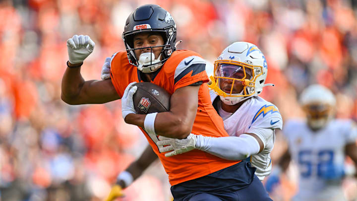 DENVER, CO - OCTOBER 13: Broncos wide receiver Devaughn Vele (17) runs the ball as Chargers cornerback Tarheeb Still (29) tries to tackle him, during a game between the Denver Broncos and the Los Angeles Chargers at Empower Field at Mile High in Denver, CO on October 13, 2024. 