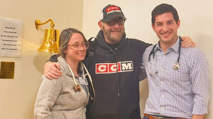 Jason Myrtetus stands with oncologist Dr. Daniel Altman (right) and Heather Levinsky, CRNP (left) after ringing the bell following his final chemo treatment. 