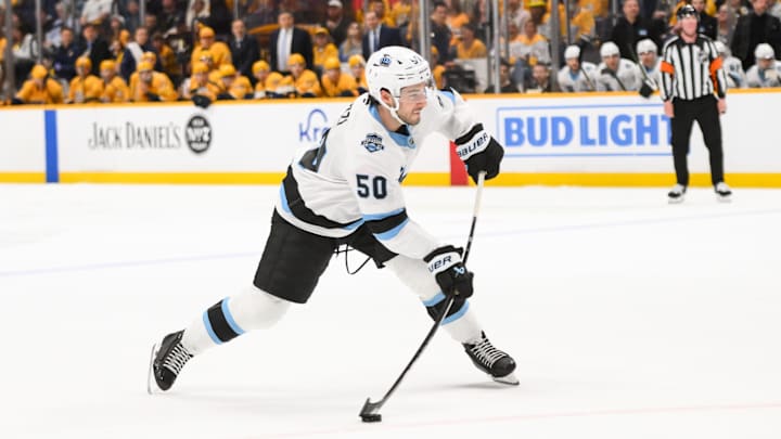 Apr 14, 2025; Nashville, Tennessee, USA;  Utah Hockey Club defenseman Sean Durzi (50) takes a shot on goal against the Nashville Predators during the second period at Bridgestone Arena. Mandatory Credit: Steve Roberts-Imagn Images