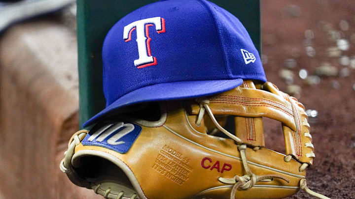 A Texas Rangers cap and baseball mitt sit on the dugout steps during a game against the Athletics at Globe Life Field.