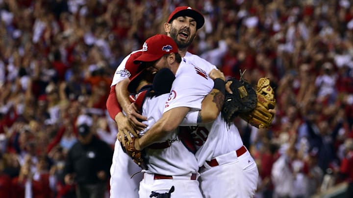 Oct 9, 2013; St. Louis, MO, USA; St. Louis Cardinals starting pitcher Adam Wainwright (right) celebrates with catcher Yadier Molina (left) and shortstop Daniel Descalso (back) after defeating the Pittsburgh Pirates in game five of the National League divisional series playoff baseball game at Busch Stadium. The Cardinals won 6-1. Mandatory Credit: Scott Rovak-Imagn Images