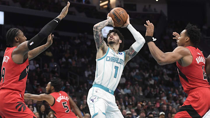 Jan 7, 2026; Charlotte, North Carolina, USA;  Charlotte Hornets guard LaMelo Ball (1) shoots as he is defended by Toronto Raptors guard RJ Barrett (9) and forward Scottie Barnes (4) during the first half at the Spectrum Center. Mandatory Credit: Sam Sharpe-Imagn Images