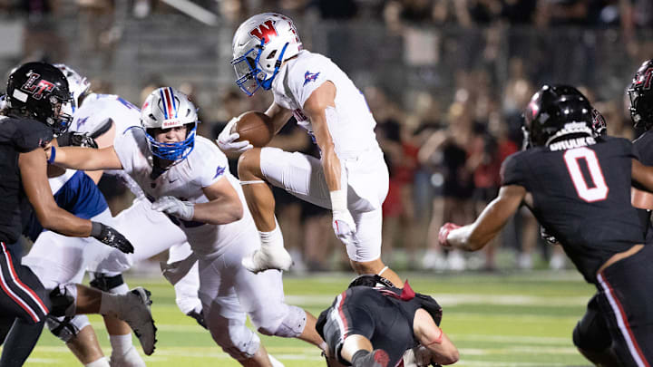Westlake hurdles through the Lake Travis defense in a 2023 high school football game in Texas.