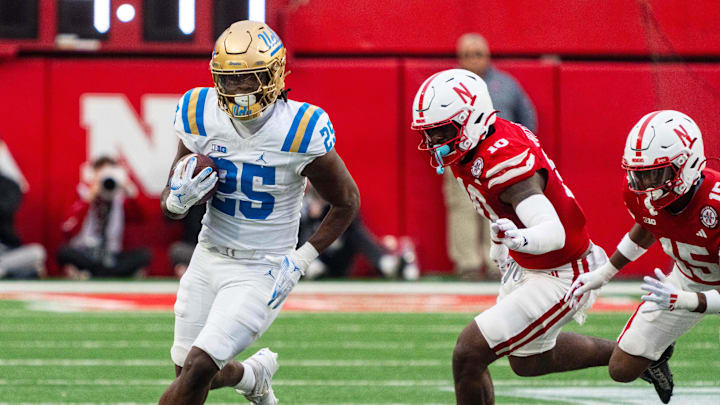 Nov 2, 2024; Lincoln, Nebraska, USA; UCLA Bruins running back T.J. Harden (25) runs the ball against Nebraska Cornhuskers defensive lineman Jimari Butler (10) during the third quarter at Memorial Stadium. Mandatory Credit: Dylan Widger-Imagn Images Nov 2, 2024; Lincoln, Nebraska, USA; UCLA Bruins running back T.J. Harden (25) runs the ball against Nebraska Cornhuskers defensive lineman Jimari Butler (10) during the third quarter at Memorial Stadium. Mandatory Credit: Dylan Widger-Imagn Images
