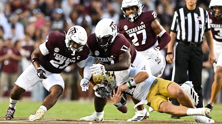 Aug 31, 2024; College Station, Texas, USA;  Texas A&M Aggies linebacker Taurean York (21) and defensive lineman Albert Regis (17) tackle Notre Dame Fighting Irish quarterback Riley Leonard (13) during the second quarter at Kyle Field. Mandatory Credit: Maria Lysaker-Imagn Images
