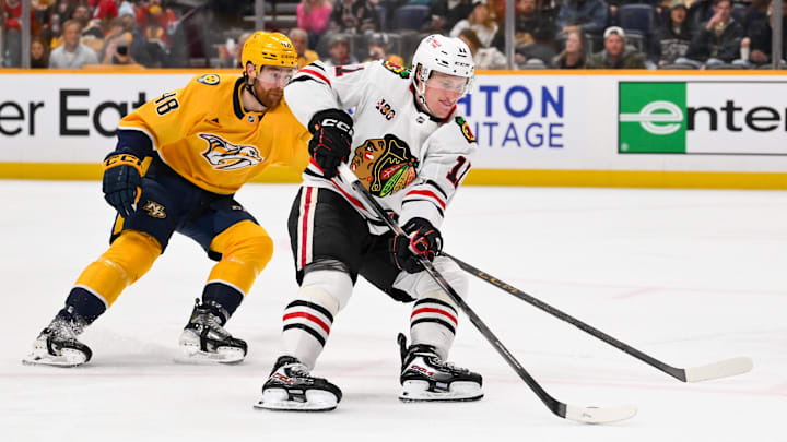 Jan 10, 2026; Nashville, Tennessee, USA;  Chicago Blackhawks center Oliver Moore (11) skates past Nashville Predators defenseman Nick Perbix (48) during the second period at Bridgestone Arena. Mandatory Credit: Steve Roberts-Imagn Images