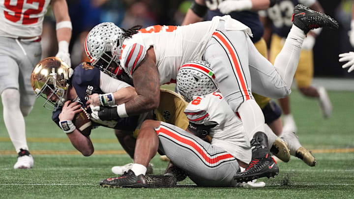 Jan 20, 2025; Atlanta, GA, USA; Notre Dame Fighting Irish quarterback Riley Leonard (13) is tackled by Ohio State Buckeyes safety Sonny Styles (6) and Ohio State Buckeyes defensive tackle Tyleik Williams (91) in the second half in the CFP National Championship college football game at Mercedes-Benz Stadium.