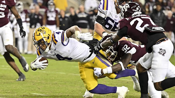 Nov 26, 2022; College Station, Texas, USA;  LSU Tigers running back John Emery Jr. (4) runs the ball against Texas A&M Aggies defensive lineman Malick Sylla (92) and defensive back Antonio Johnson (27) during the third quarter at Kyle Field. Mandatory Credit: Maria Lysaker-Imagn Images