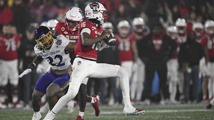 Dec 28, 2024; Annapolis, MD, USA;  North Carolina State Wolfpack quarterback CJ Bailey (16)] scrambles away from East Carolina Pirates linebacker Ryheem Craig (32) during the first half of the Go Bowling Military Bowl at Navy-Marine Corps Memorial Stadium. Mandatory Credit: Tommy Gilligan-Imagn Images