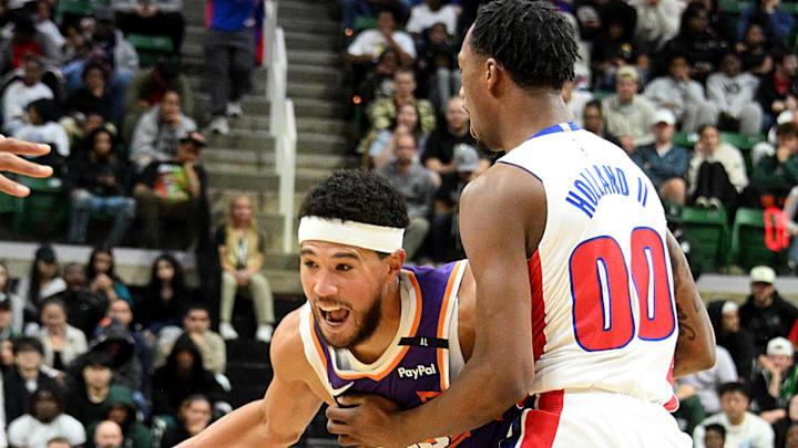 Oct 8, 2024; East Lansing, Michigan, USA;  Phoenix Suns guard Devin Booker (1) drives around Detroit Pistons forward Ron Holland II (00) at Jack Breslin Student Events Center. Mandatory Credit: Dale Young-Imagn Images