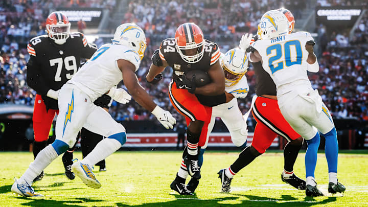 Nov 3, 2024; Cleveland, Ohio, USA; Cleveland Browns running back Nick Chubb (24) runs with the ball between Los Angeles Chargers linebacker Daiyan Henley (0) and cornerback Cam Hart (20) during the second half at Huntington Bank Field. Mandatory Credit: Ken Blaze-Imagn Images