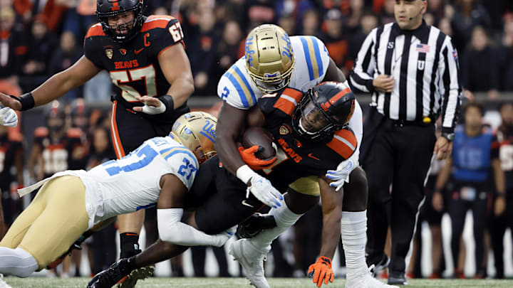 Oct 14, 2023; Corvallis, Oregon, USA; Oregon State Beavers running back Deshaun Fenwick (1) is tackled by UCLA Bruins defensive back Kamari Ramsey (27) and linebacker Oluwafemi Oladejo (2) during the first half at Reser Stadium. Mandatory Credit: Soobum Im-Imagn Images
