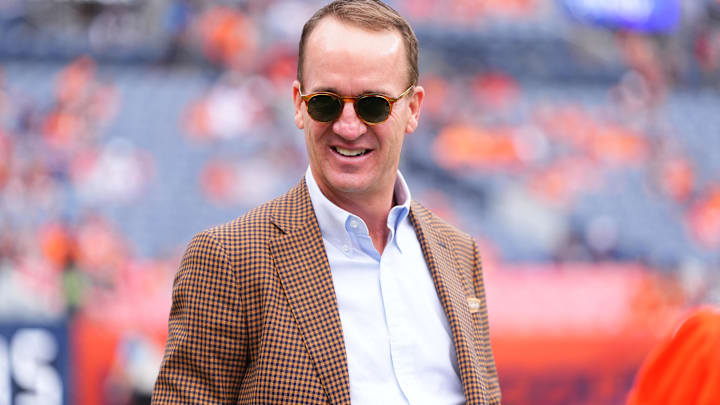 Oct 27, 2024; Denver, Colorado, USA; Retired NFL player Peyton Manning stands on the sidelines of Empower Field at Mile High before the game between the Carolina Panthers Denver Broncos. Mandatory Credit: Ron Chenoy-Imagn Images