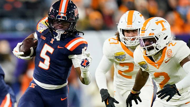 Illinois running back Ca'Lil Valentine (5) runs the ball ahead of Tennessee defensive back Andre Turrentine (2) and linebacker Jadon Perlotte (27) for a first down in the first quarter of the Music City Bowl against Tennessee in an NCAA football game on Dec. 30, 2025, in Nashville, Tennessee.