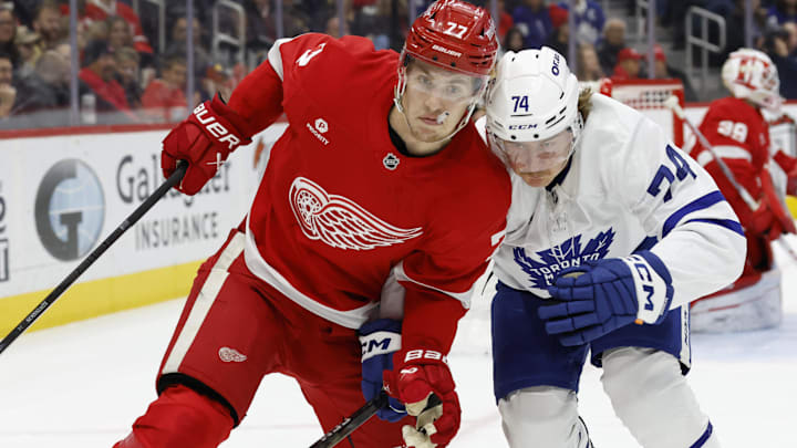 Dec 27, 2024; Detroit, Michigan, USA;  Detroit Red Wings defenseman Simon Edvinsson (77) and Toronto Maple Leafs center Bobby McMann (74) fight for position in the first period at Little Caesars Arena. Mandatory Credit: Rick Osentoski-Imagn Images