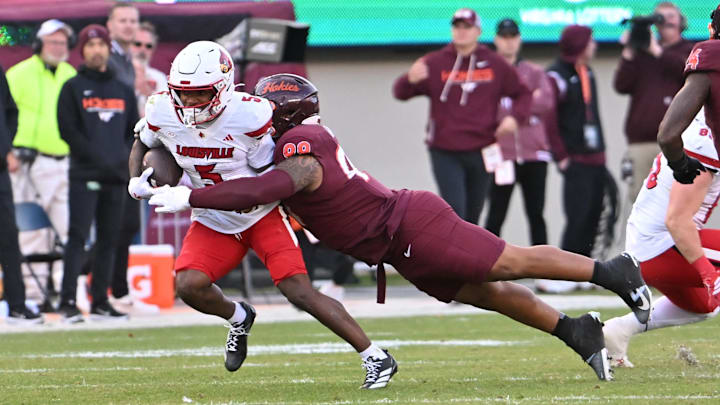 Nov 1, 2025; Blacksburg, Virginia, USA; Virginia Tech Hokies defensive lineman Emmett Laws (99) tackles Louisville Cardinals wide receiver Caullin Lacy (5) during the fourth quarter at Lane Stadium. Mandatory Credit: Brian Bishop-Imagn Images