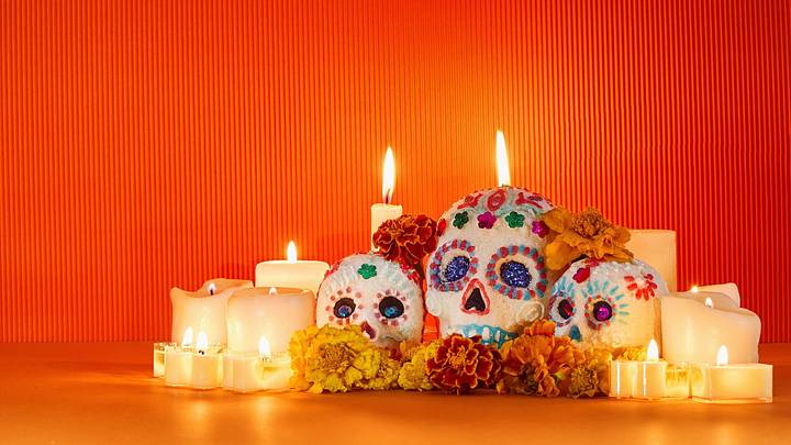 Colorful sugar skulls and marigolds on a candlelit altar for Dia de los Muertos. Colorful sugar skulls and marigolds on a candlelit altar for Dia de los Muertos.