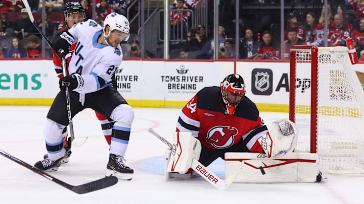 Oct 14, 2024; Newark, New Jersey, USA; New Jersey Devils goaltender Jake Allen (34) makes a save while Utah Hockey Club center Barrett Hayton (27) looks for the rebound during the first period at Prudential Center. Mandatory Credit: Ed Mulholland-Imagn Images