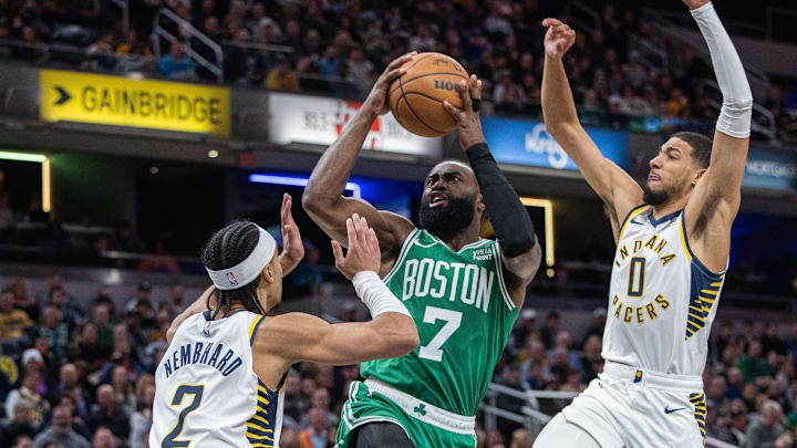 Jan 8, 2024; Indianapolis, Indiana, USA; Boston Celtics guard Jaylen Brown (7) shoots the ball while Indiana Pacers guard Andrew Nembhard (2) and guard Tyrese Haliburton (0)  defend in the first half at Gainbridge Fieldhouse. Mandatory Credit: Trevor Ruszkowski-Imagn Images
