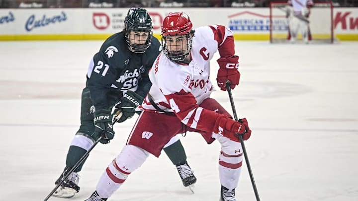Wisconsin defenseman Ben Dexheimer (4) handles the puck as Michigan State forward Anthony Romani (21) chases him in a game Friday, January 16, 2026, at the Kohl Center in Madison, Wisconsin.