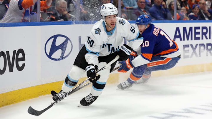 Oct 10, 2024; Elmont, New York, USA; Utah Hockey Club defenseman Sean Durzi (50) controls the puck against New York Islanders right wing Simon Holmstrom (10) during the second period at UBS Arena. Mandatory Credit: Brad Penner-Imagn Images