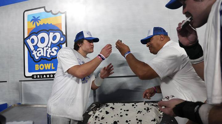 Dec 27, 2025; Orlando, FL, USA; BYU Cougars quarterback Bear Bachmeier (47) and head coach Kalani Sitake are presented a large pop-tart to eat after they beat the against the Georgia Tech Yellow Jackets at Camping World Stadium. Mandatory Credit: Kim Klement Neitzel-Imagn Images