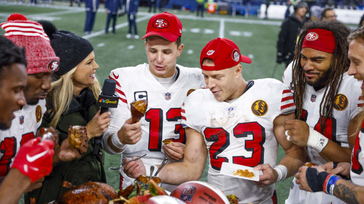 Nov 23, 2023; Seattle, Washington, USA; San Francisco 49ers quarterback Brock Purdy (13), running back Christian McCaffrey (23) and San Francisco 49ers linebacker Fred Warner (54) partake in a turkey dinner following a 31-13 victory against the Seattle Seahawks at Lumen Field. Mandatory Credit: Joe Nicholson-USA TODAY Sports