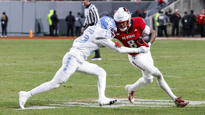 Nov 29, 2025; Raleigh, North Carolina, USA;  NC State Wolfpack wide receiver Keenan Jackson (8) runs with the ball guarded by North Carolina Tar Heels defensive back Tre Miller (15) during the second half of the game at Carter-Finley Stadium.  Mandatory Credit: Jaylynn Nash-Imagn Images