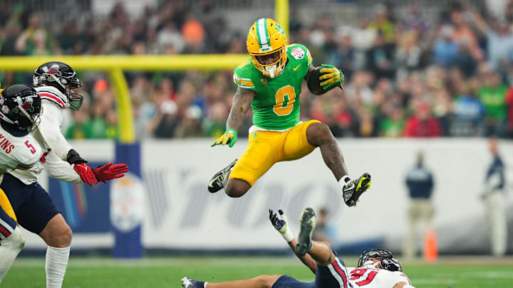 Jan 1, 2024; Glendale, AZ, USA; Oregon Ducks running back Bucky Irving (0) hurdles over Liberty defender.