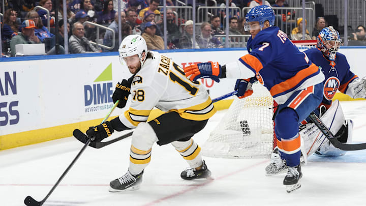 Nov 26, 2025; Elmont, New York, USA; Boston Bruins center Pavel Zacha (18) and New York Islanders right wing Maxim Tsyplakov (7) battle for control of the puck in the third period at UBS Arena. Mandatory Credit: Wendell Cruz-Imagn Images