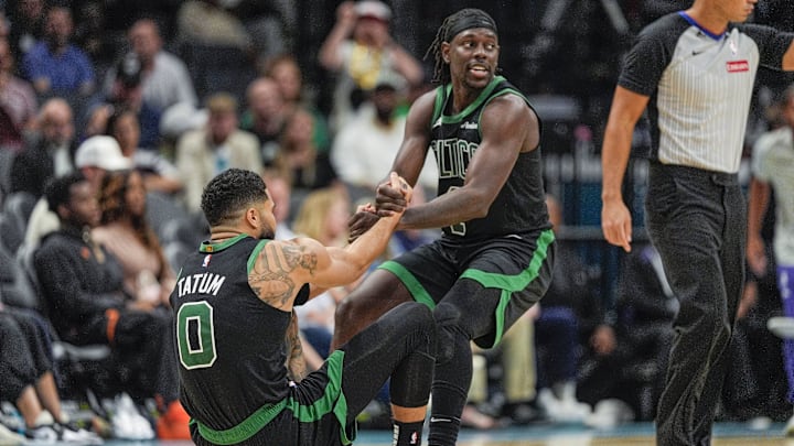 Nov 1, 2024; Charlotte, North Carolina, USA; Boston Celtics guard Jrue Holiday (4) helps forward Jayson Tatum (0) onto his feet after a foul late during the second half against the Charlotte Hornets at the Spectrum Center. Mandatory Credit: Jim Dedmon-Imagn Images