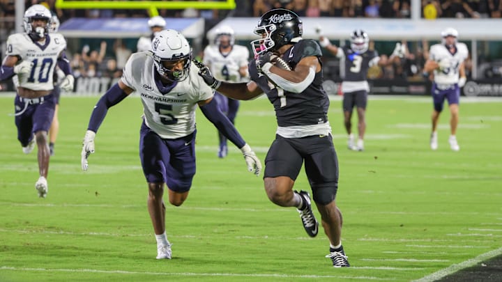 Aug 29, 2024; Orlando, Florida, USA; UCF Knights running back RJ Harvey (7) runs the ball against New Hampshire Wildcats defensive back Wande Owens (5) during the second quarter at FBC Mortgage Stadium. Mandatory Credit: Mike Watters-USA TODAY Sports