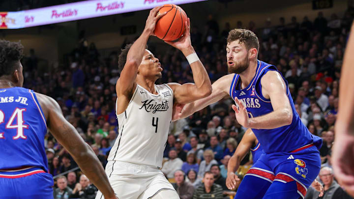 Jan 5, 2025; Orlando, Florida, USA; UCF Knights guard Keyshawn Hall (4) goes to the basket against Kansas Jayhawks center Hunter Dickinson (1) during the first half at Addition Financial Arena. Mandatory Credit: Mike Watters-Imagn Images