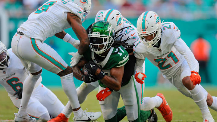 Dec 8, 2024; Miami Gardens, Florida, USA; New York Jets wide receiver Davante Adams (17) is stopped by Miami Dolphins linebacker Jordyn Brooks (20), safety Jordan Poyer (21), and safety Jevon Holland (8) afte running with the football during the second quarter at Hard Rock Stadium.