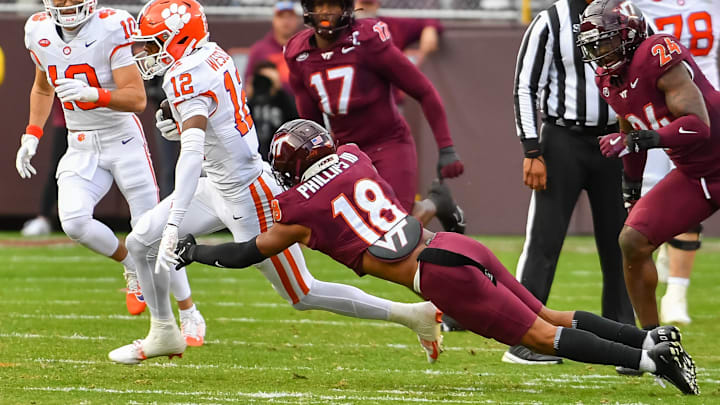 Nov 9, 2024; Blacksburg, Virginia, USA;  .Virginia Tech Hokies safety Mose Phillips III (18) dives to tackle Clemson Tigers cornerback Corian Gipson (12) during the first quarter at Lane Stadium. Mandatory Credit: Brian Bishop-Imagn Images