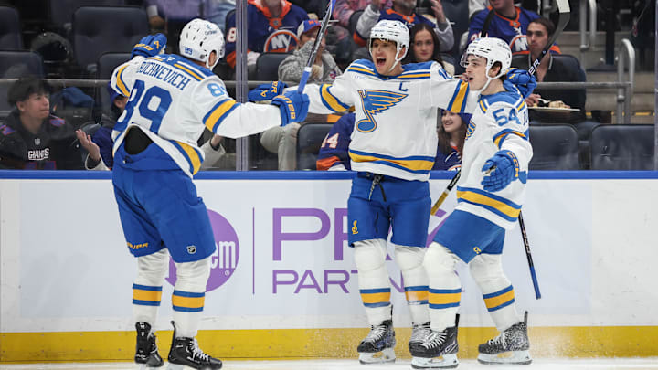 Nov 22, 2025; Elmont, New York, USA;  St. Louis Blues center Brayden Schenn (10) celebrates with left wing Pavel Buchnevich (89) and right wing Dalibor Dvorsky (54) after scoring a goal in the first period against the New York Islanders at UBS Arena. Mandatory Credit: Wendell Cruz-Imagn Images