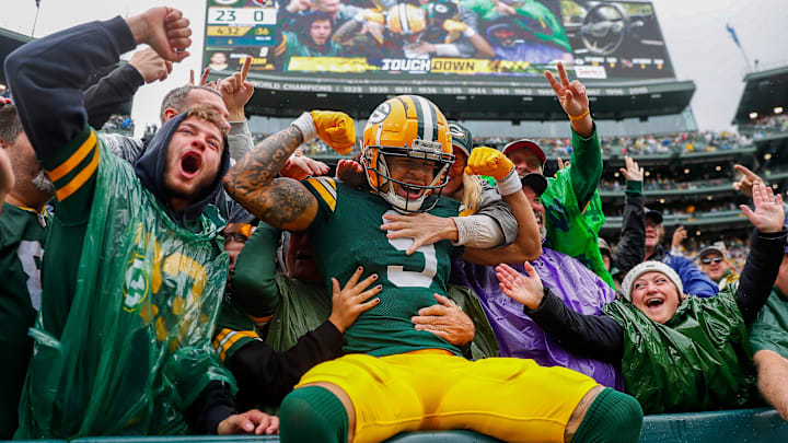Green Bay Packers wide receiver Christian Watson (9) flexes as he does a “Lambeau Leap” with Packers fans.