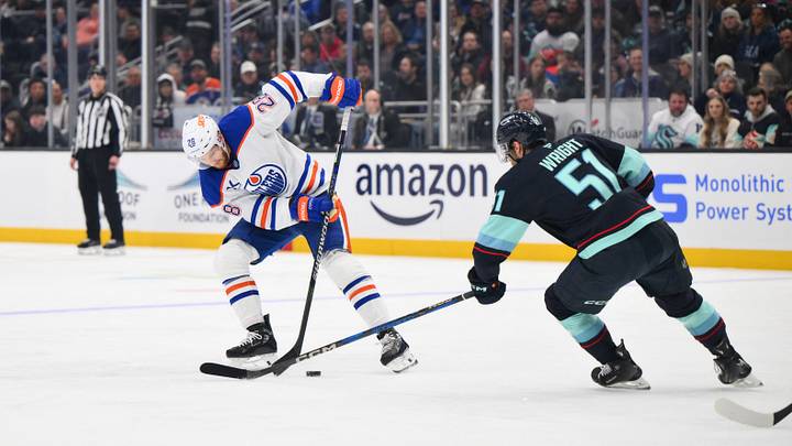 Mar 27, 2025; Seattle, Washington, USA; Edmonton Oilers right wing Connor Brown (28) plays the puck while defended by Seattle Kraken center Shane Wright (51) during the first period at Climate Pledge Arena. Mandatory Credit: Steven Bisig-Imagn Images