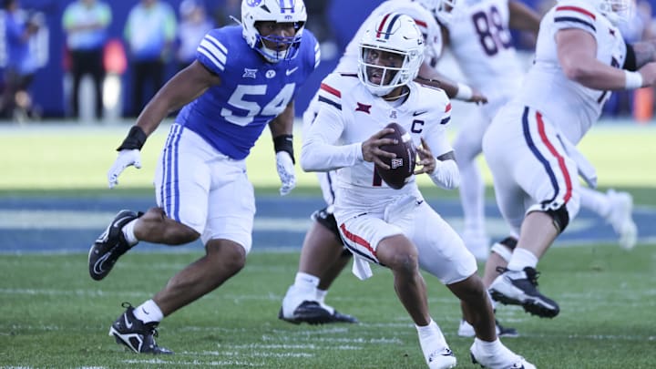 Oct 12, 2024; Provo, Utah, USA; Arizona Wildcats quarterback Noah Fifita (11) is rushed by Brigham Young Cougars linebacker Siale Esera (54) during the fourth quarter at LaVell Edwards Stadium. 