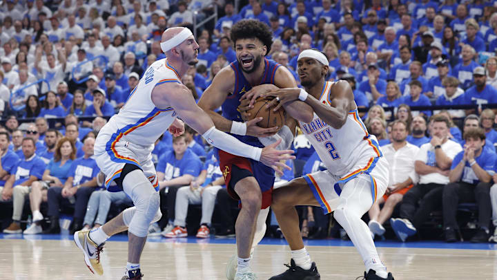 Denver Nuggets guard Jamal Murray (27) drives between Oklahoma City Thunder guard Alex Caruso (9) and guard Shai Gilgeous-Alexander (2) during the second quarter of game five of the second round for the 2025 NBA Playoffs at Paycom Center. Mandatory Credit: Alonzo Adams-Imagn Images