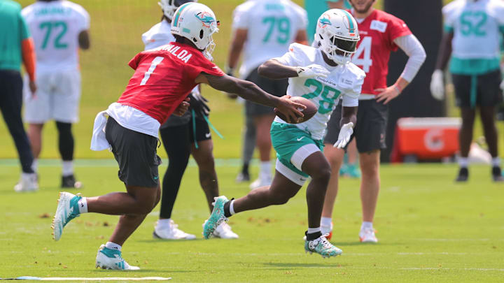 Miami Dolphins quarterback Tua Tagovailoa (1) handoffs the football to running back De'Von Achane (28) during mandatory minicamp at Hard Rock Stadium.